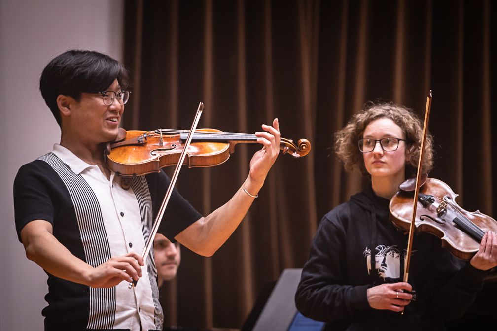 Siwoo Kim coaching a young violinist in a masterclass, both with violins raised
